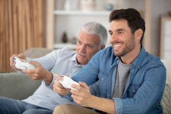 excited millennial man and senior father playing videogames