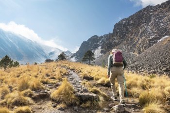 Mountaineer walking along a path full of grass surrounded by landscape with mountains  in Mexico