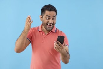 Smiling young man having fun while using Smartphone 