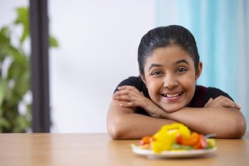 Close-up portrait of a cheerful girl with a plate of vegetable salad