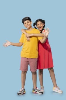 Portrait of brother and sister embracing against blue background