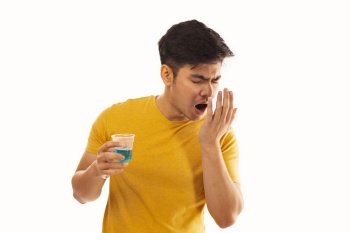 Young man smelling his breath after using mouthwash