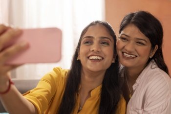 Close-up portrait of two smiling young women taking selfie together