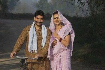 Portrait of a happy rural couple standing on a street in village.