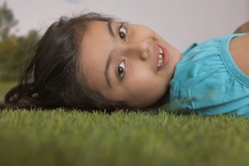young girl lying down on grass