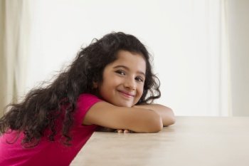 Portrait of a young girl sitting and smiling at home. (Children) 
