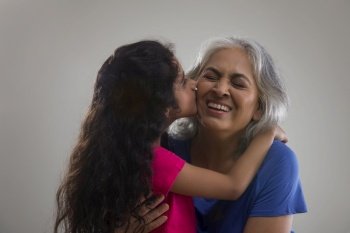 Portrait of a happy grand-daughter kissing her grandmother.   