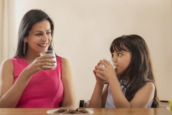 A MOTHER LOOKING AT HER DAUGHTER WHILE DRINKING MILK