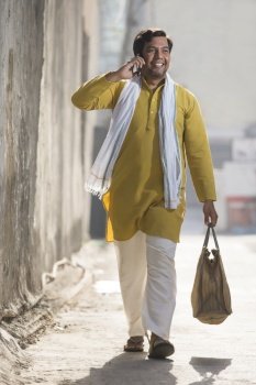 A RURAL MAN HAPPILY WALKING WHILE TALKING OVER PHONE
