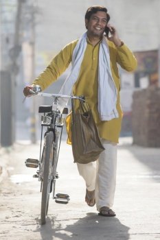 A RURAL MAN WALKING WITH BICYCLE TALKING OVER PHONE