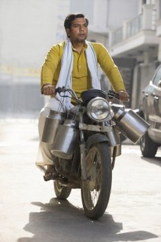 A VILLAGER RIDING MOTORCYCLE TO DELIVER MILK