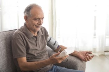 Senior man taking his blood pressure test at home. (Health and fitness) 