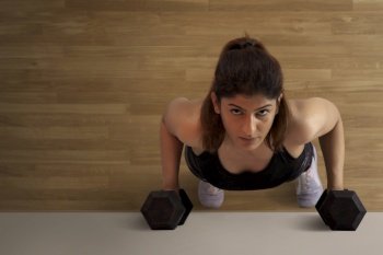 Woman doing pushups with dumbbells. 