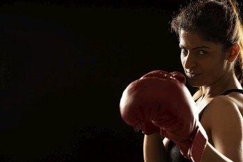 Woman wearing boxing gloves ready to throw a punch. 