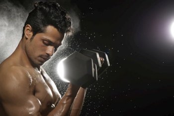 Man working out with dumbbells over a dark background. 