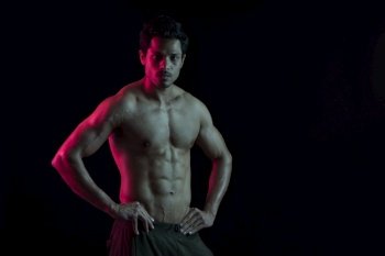 Man flexing his muscles in front of a dark background. 