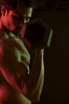 Man working out with dumbbells over a dark background. 
