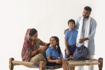 PORTRAIT OF A RURAL GIRL IN SCHOOL UNIFORM LAUGHING WITH MOTHER WITH BROTHER AND FATHER BESIDES 