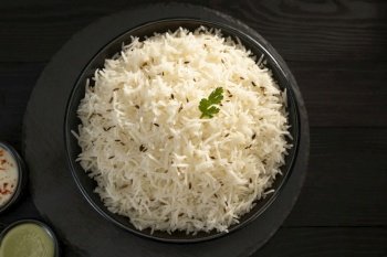 Steamed rice with Zeera  in a balck bowl with green chutney and curd