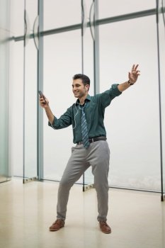 A HAPPY CORPORATE PROFESSIONAL DANCING WHILE HOLDING MOBILE PHONE