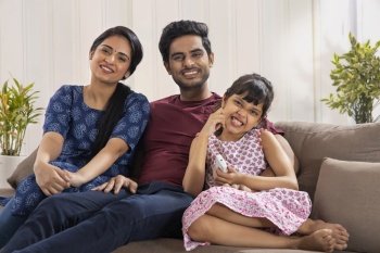 A HAPPY FAMILY PLAYFULLY POSING WHILE SITTING AT HOME