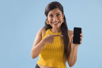 A young woman pointing towards her mobile phone.