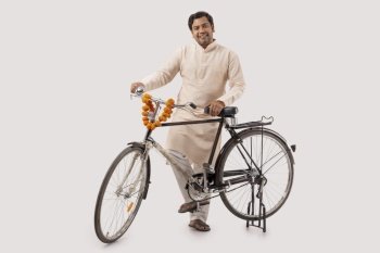 A HAPPY RURAL MAN STANDING WITH BICYCLE AND POSING