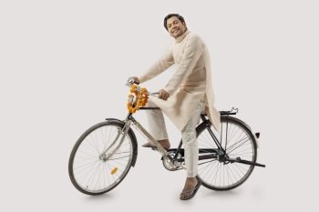 A RURAL MAN HAPPILY POSING WHILE SITTING ON NEW BICYCLE