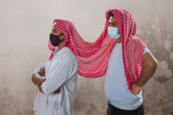 TWO LABOURERS WITH FACE MASK STANDING AND LOOKING AWAY