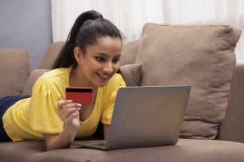 A young woman with laptop and credit card shopping online. 