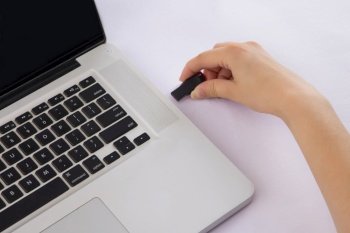 Human hand inserting pen-drive into laptop.