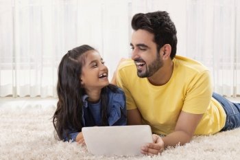 A FATHER AND DAUGHTER LAUGHING TOGETHER WHILE RELAXING AT HOME