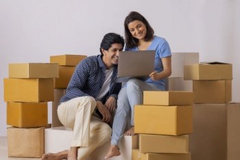 Indian middle age couple together watching laptop on stairs in new room