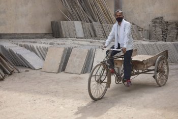 A LABOURER LOOKING AT CAMERA WHILE PULLING A CART AT A CONSTRUCTION SITE