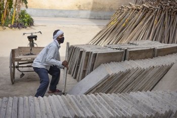 A LABOURER CARRYING LARGE BLOCK OF TILE