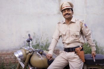 Portrait of an Indian policeman posing with bike