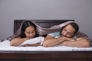 Couple sleeping together under blanket on bed 