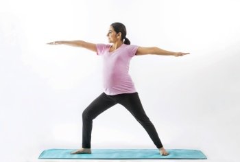 Pregnant woman practicing yoga in a warrior position. 