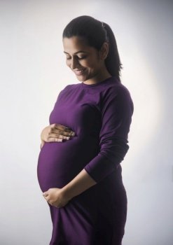 Pregnant woman smiling at her baby bump. 