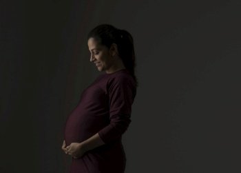 Pregnant woman smiling with her hands on her baby bump. 
