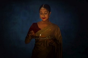 Indian lady in golden saree holding puja thaali on Diwali