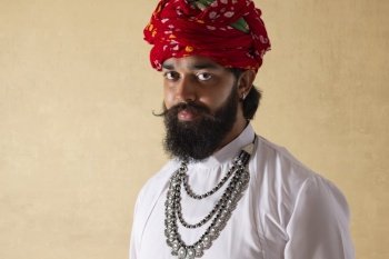 Close-up portrait of Rajasthani young man standing against plain background