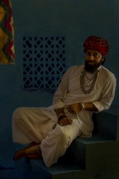 Portrait of smiling Rajasthani man leaning on stair at home