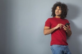 A YOUNG MAN LOOKING AWAY WHILE USING MOBILE PHONE