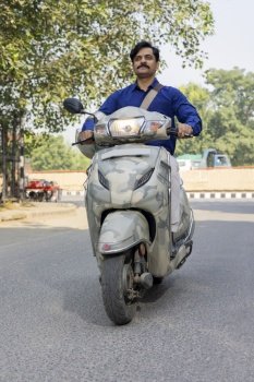 Common man riding a scooty on city street