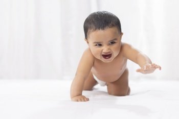 Cute baby in diaper crawling on bed