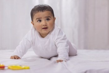 Cute little child crawling on bed alone
