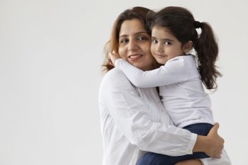 A DAUGHTER HUGGING HER MOTHER AND LOOKING AT CAMERA