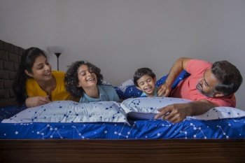Portrait of happy family having fun together on bed