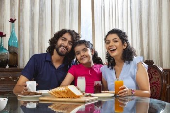  Family members posing in front of camera while sitting together at breakfast table with drinks at home